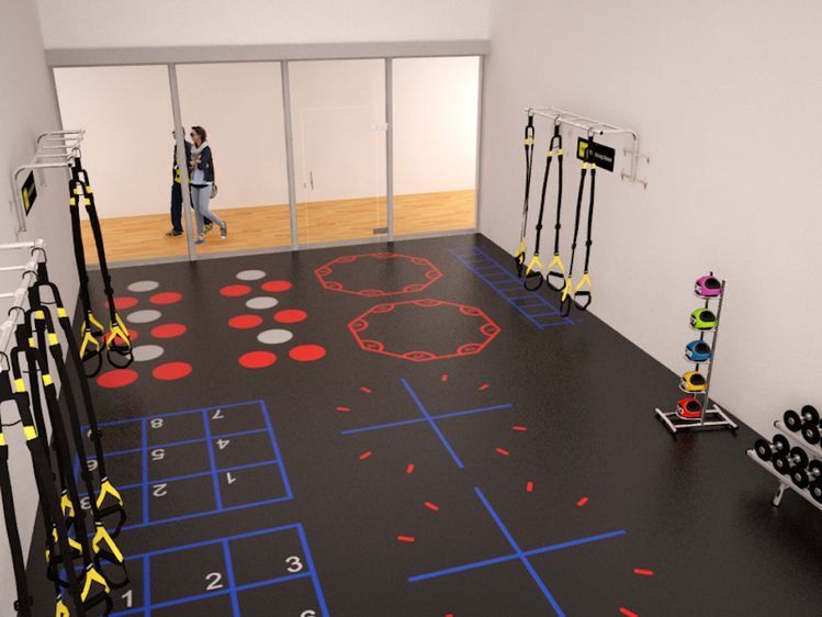 Open training floor with marked stations and resistance equipment along the walls